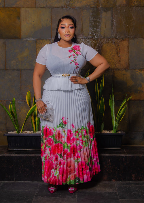 Blossom Beauty white Miyake pleated maxi skirt set featuring a floral peplum top, pearl buckle waist belt and flowing pink rose-print skirt.
