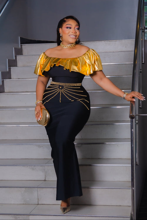 Black and gold off-shoulder bandage maxi dress with metallic gold ruffle neckline and decorative gold beadwork at the waist.