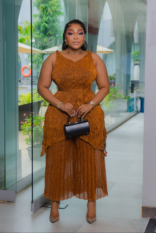 Model wearing Serena Shimmer copper brown Miyake pleated two-piece set featuring a sleeveless top and matching shimmering capri pants.